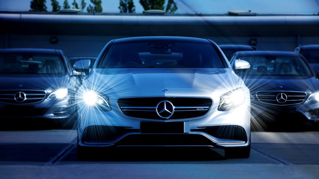 Front view of a lineup of Mercedes-Benz cars with bright headlights, showcasing luxury and elegance.