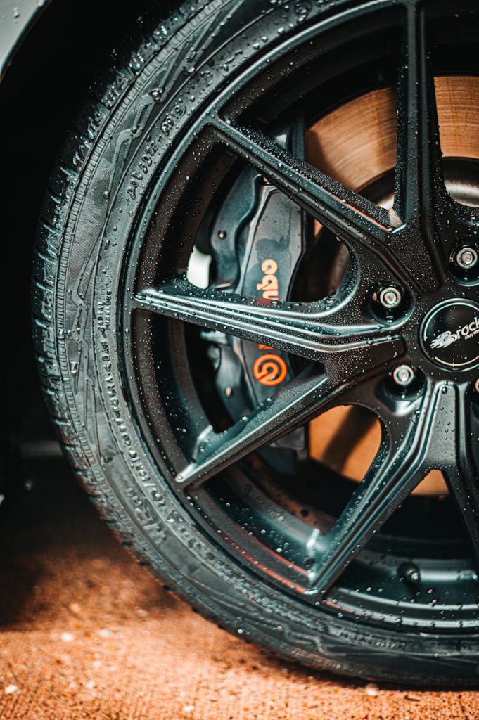 Detailed photo of a black alloy wheel with visible water droplets and a prominent Brembo brake caliper.