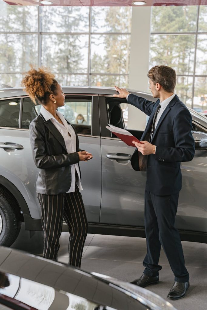 A woman and a car salesman discuss vehicle options inside a dealership.